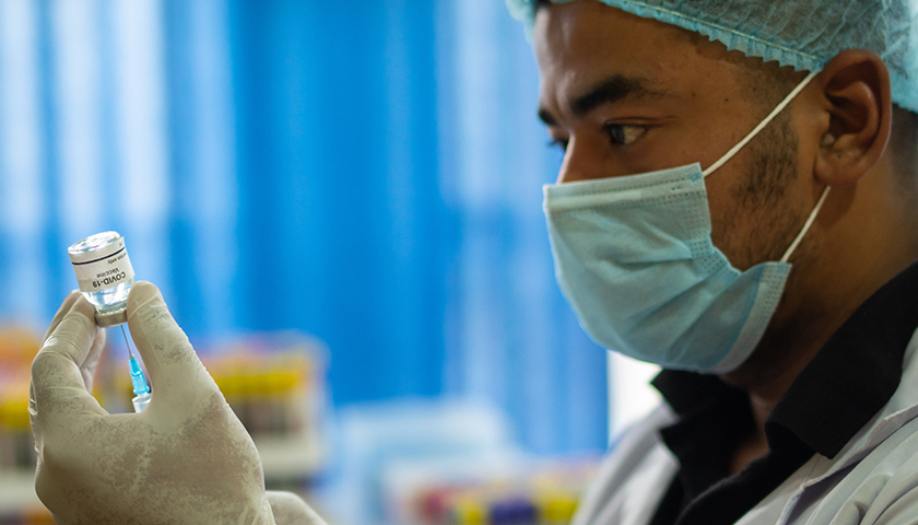 Doctor with mask on holding COVID-19 Vaccine