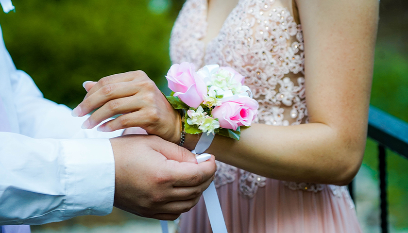 Boy putting on a corsage on woman's wrist