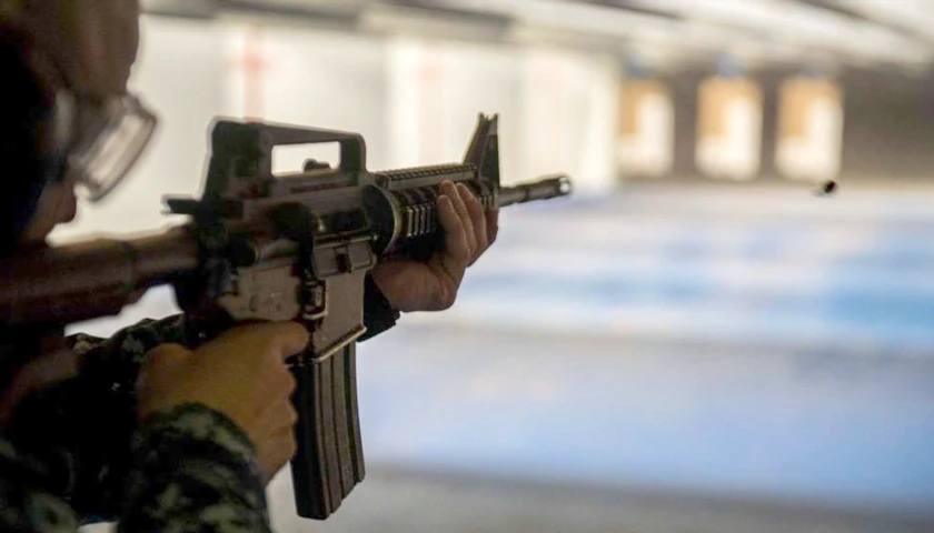 Person practicing marksmanship at shooting range with AR-15 style rifle